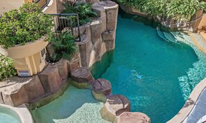 Piscina com água azul cristalina, rodeada por formações rochosas e vegetação.