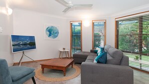 A living room with a sofa, a coffee table, a TV, and artwork on the wall.