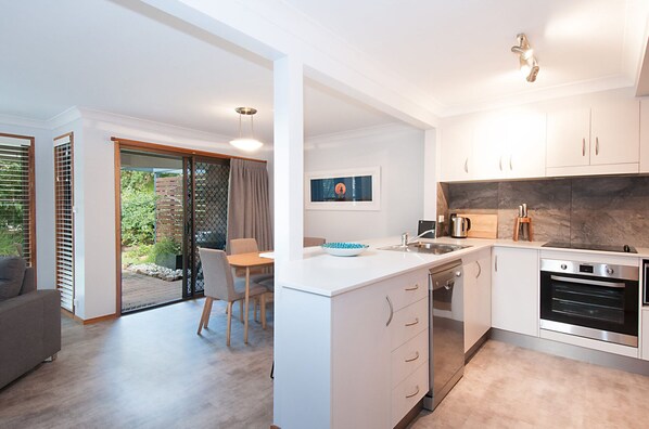 Enjoy a comfortable stay in this stylish apartment with a sofa, dining table, and kitchen featuring a stove and sink.