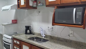A kitchen with a built-in microwave, a coffee maker, and a sink. - Located 150 meters from the most charming beach in Arraial do Cabo, this 2-bedroom apartment features air conditioning! (Arraial do Cabo)