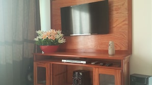 A wooden entertainment center with a flat-screen TV mounted above it. - Located 150 meters from the most charming beach in Arraial do Cabo, this 2-bedroom apartment features air conditioning! (Arraial do Cabo)