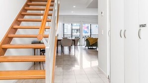 A modern interior with a wooden staircase leading to a dining area and a living space. - Byron Bay Accom - Solace 1 - 8 Lawson Street (Byron Shire)