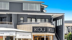 A modern building with a prominent 'KOU KOU' sign, a visible storefront, and a balcony with a railing. - Byron Bay Accom - Solace 1 - 8 Lawson Street (Byron Shire)