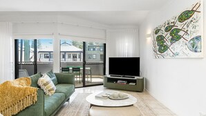 A modern living room with a green sofa, a flat-screen TV, and a coffee table. - Byron Bay Accom - Solace 1 - 8 Lawson Street (Byron Shire)