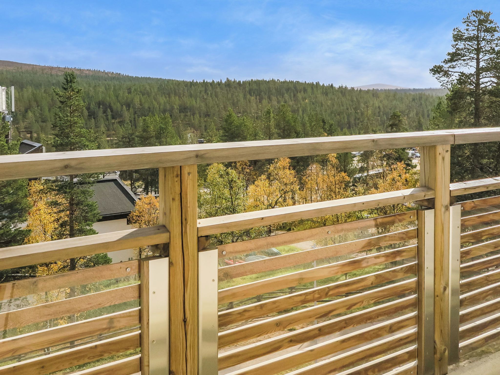 Un balcon en bois offrant une vue sur une colline boisée.