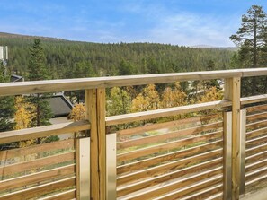 A wooden balcony with a view of a forested hillside.