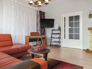 Una sala de estar moderna con un sofá, un televisor montado en la pared, una chimenea y una puerta con letrero de privacidad.