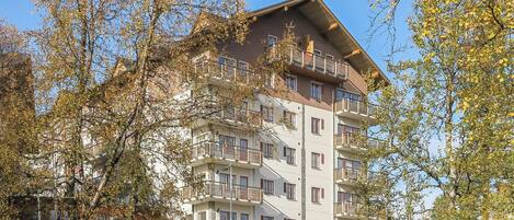 Ein mehrstöckiges Hotel mit Balkonen, umgeben von Bäumen.