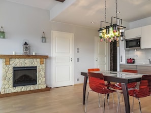 Una cocina moderna con chimenea de piedra, una mesa de comedor con sillas y un lámpara colgante.