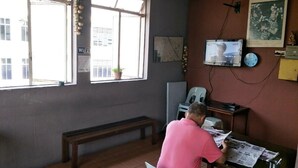 A room with a large window, a desk, a chair, and a bench.