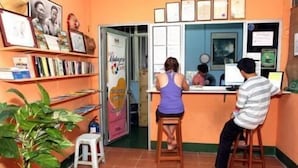 A small office with a desk, chairs, and a bookshelf with framed pictures.