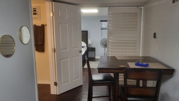 A room with a dining table, chairs, a fan, and a closed door.