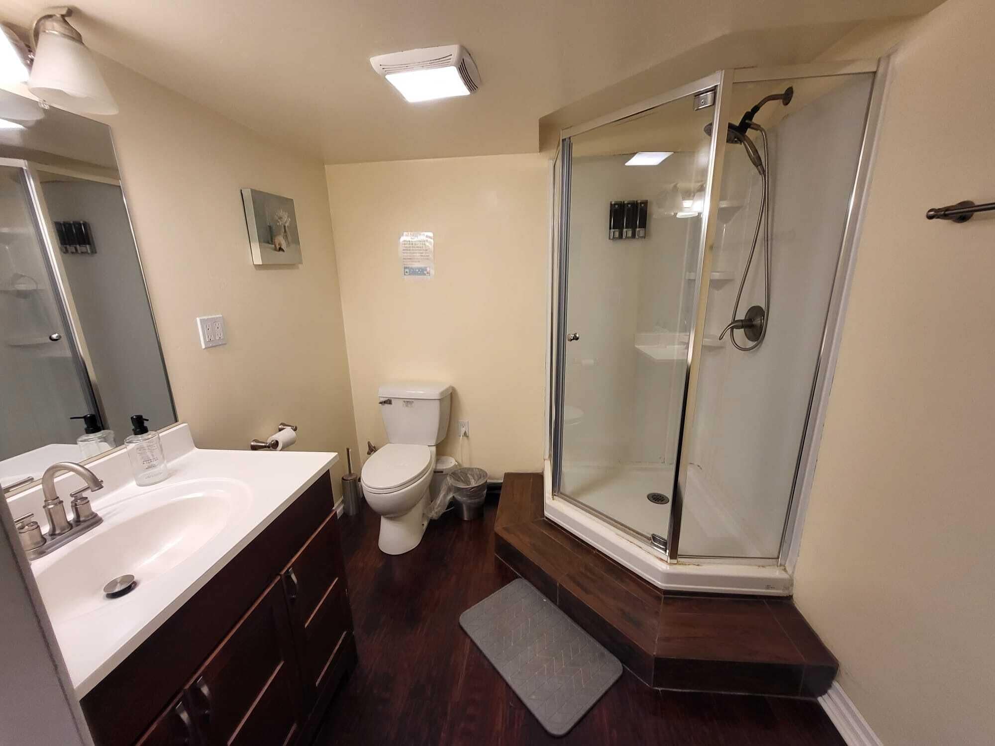 A bathroom with a white sink, a toilet, and a glass-enclosed shower.