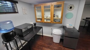 A compact kitchen with a microwave, coffee maker, water dispenser, and a refrigerator.