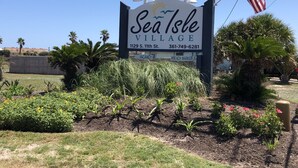 A sign for Sea Isle Village with a clear view of the address and contact number.