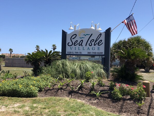 A sign for Sea Isle Village with a clear view of the address and contact number.