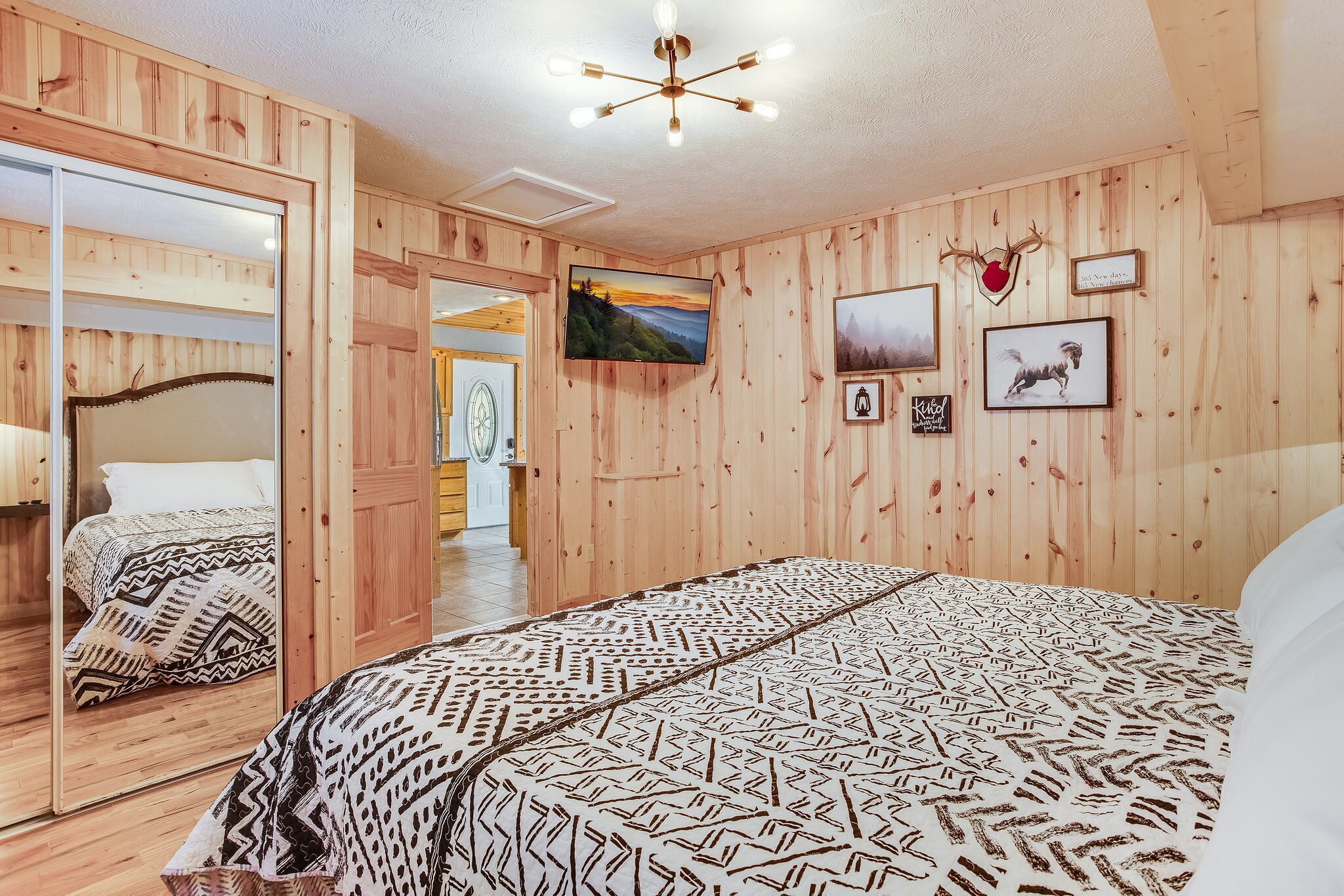 Una habitación con paneles de madera, una cama, un televisor y un espejo.