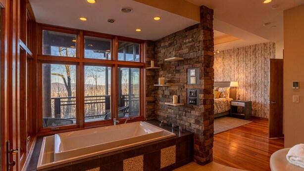 Une salle de bain dotée d’une grande fenêtre, d’un mur décoratif en pierre et d’un plancher en bois.