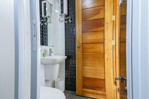 A bathroom with a toilet, sink, and a wooden door.