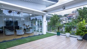 Ein modernes Wohnzimmer mit Glastür, Holzboden und einem kleinen Balkon mit Topfpflanzen.