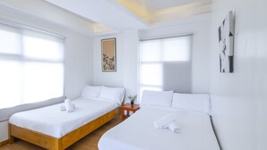 Ein Hotelzimmer mit zwei Einzelbetten, Holz-Kopfteilen, weißer Bettwäsche und einem kleinen Nachttisch mit einer Vase.