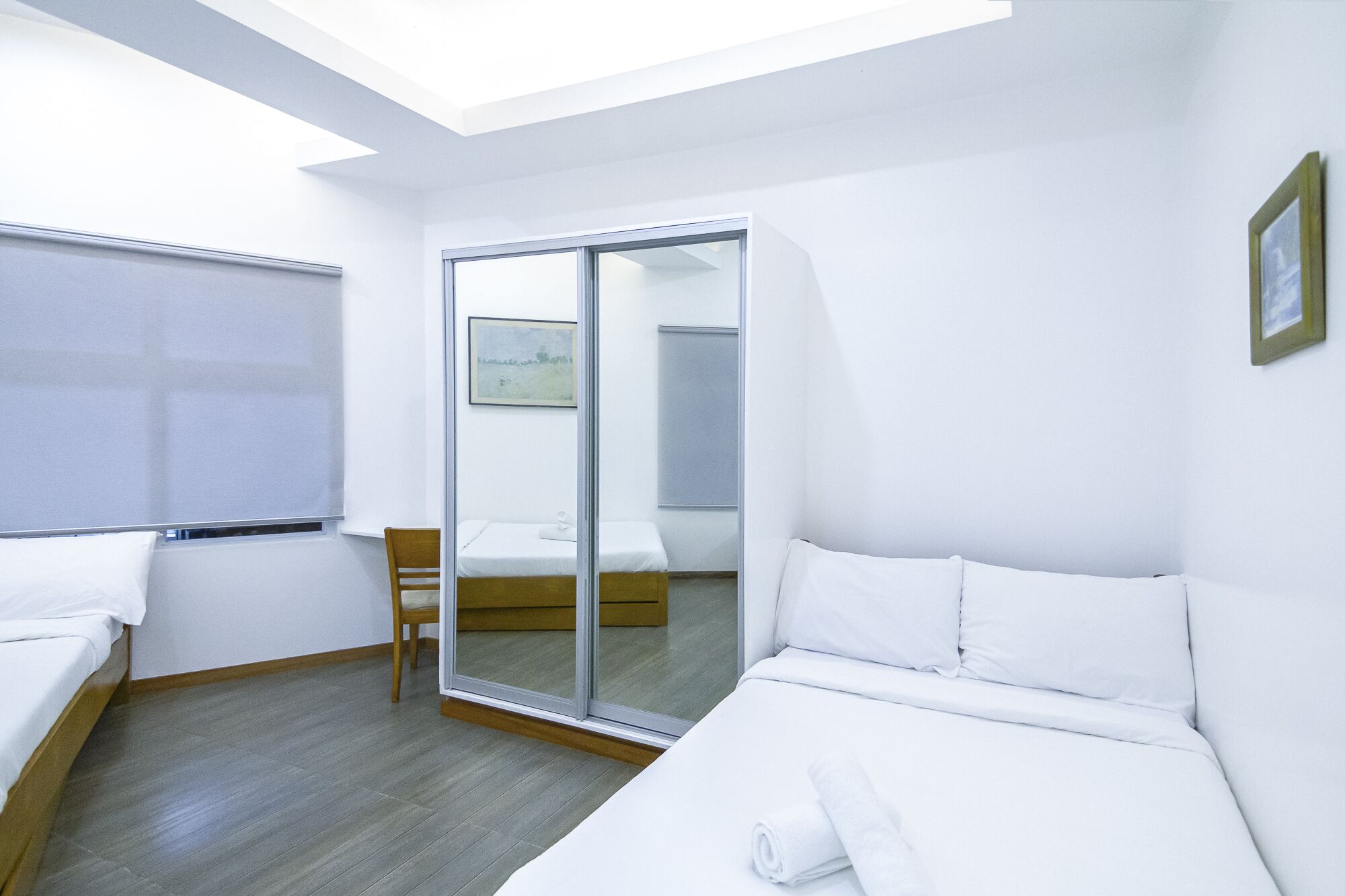 A modern hotel room with a skylight, a sliding glass door leading to a bathroom, and a neatly made bed.