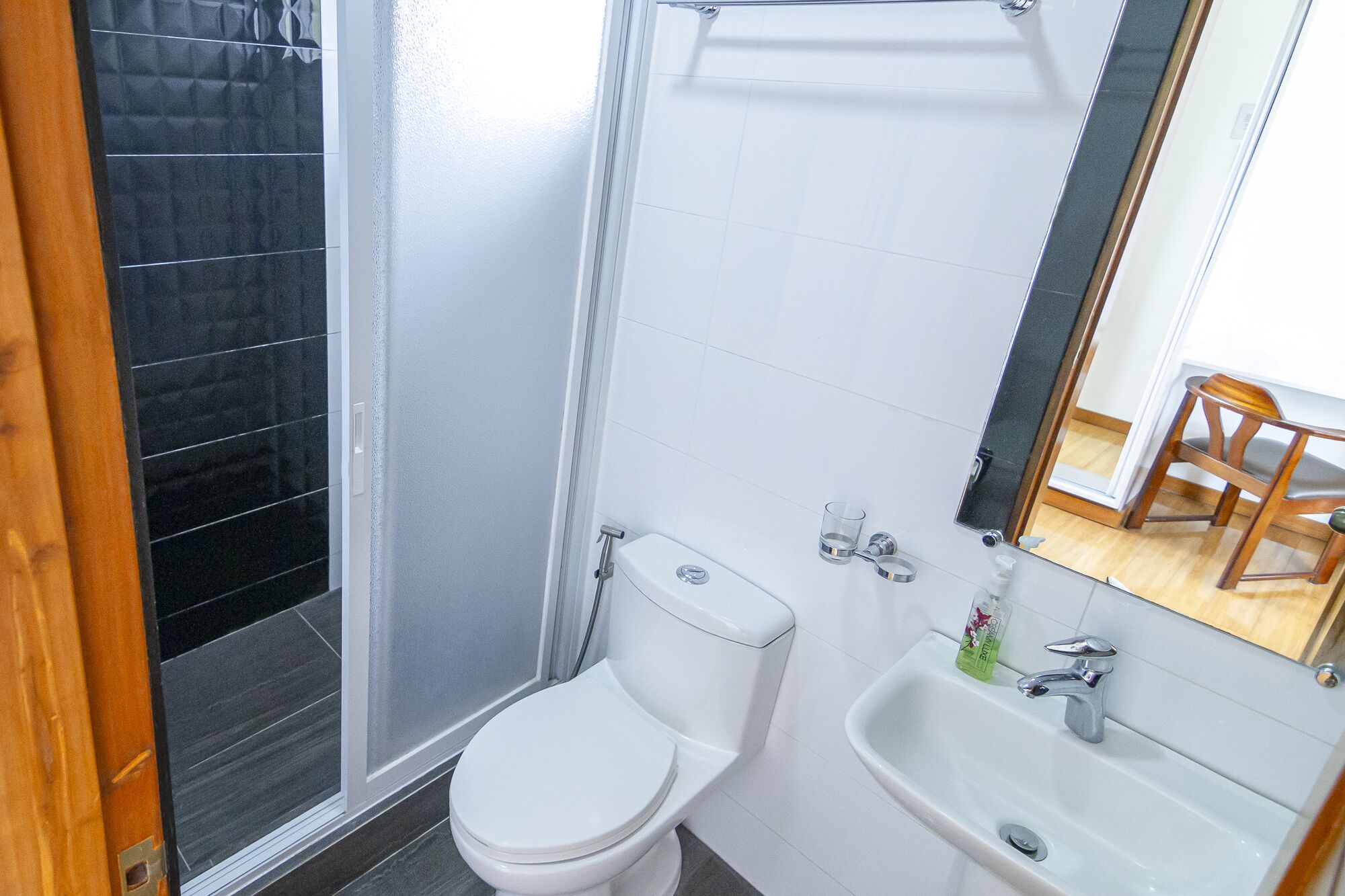 Un baño con inodoro blanco, lavabo y zona de ducha.