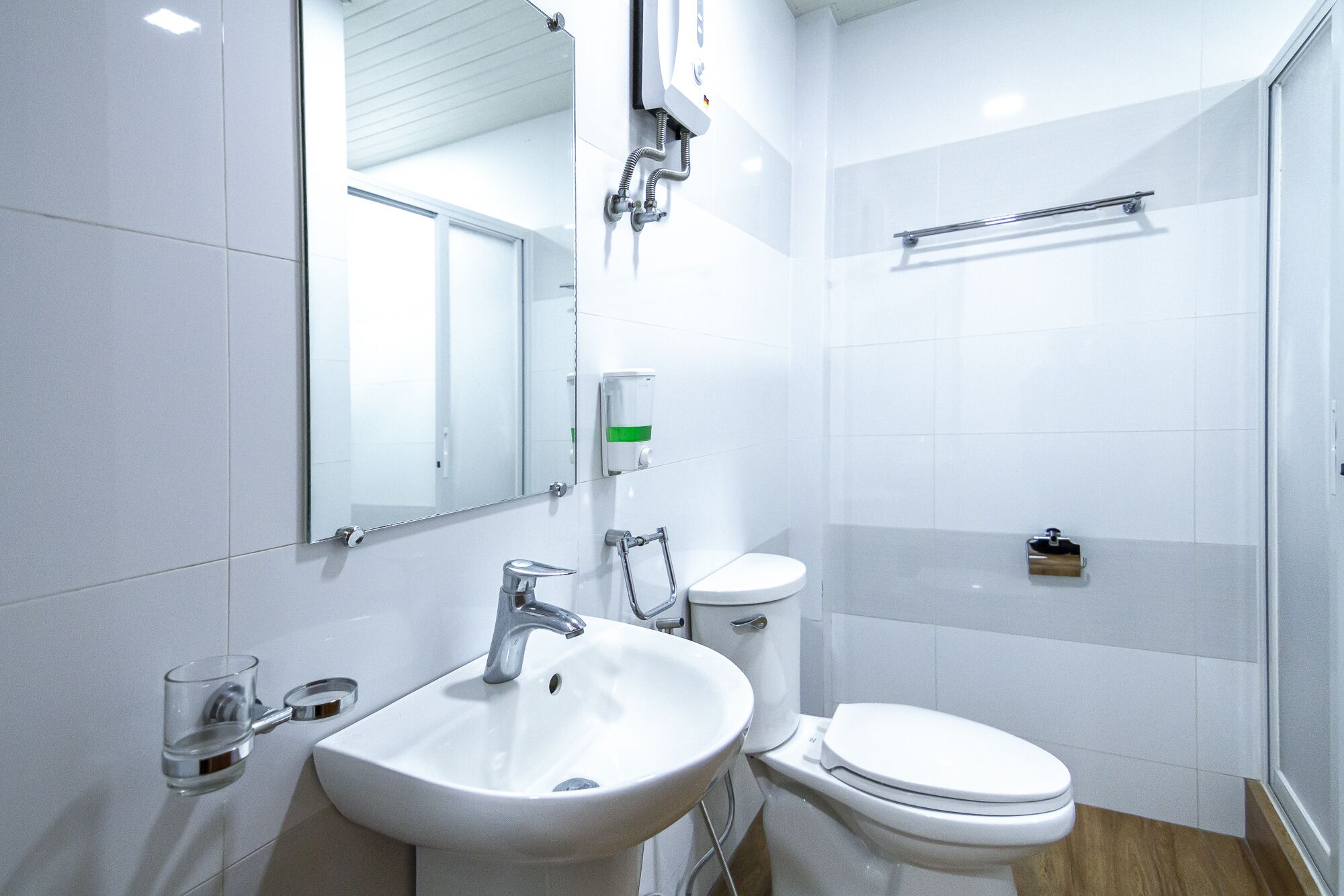 A modern bathroom with a sink, mirror, toilet, and shower.