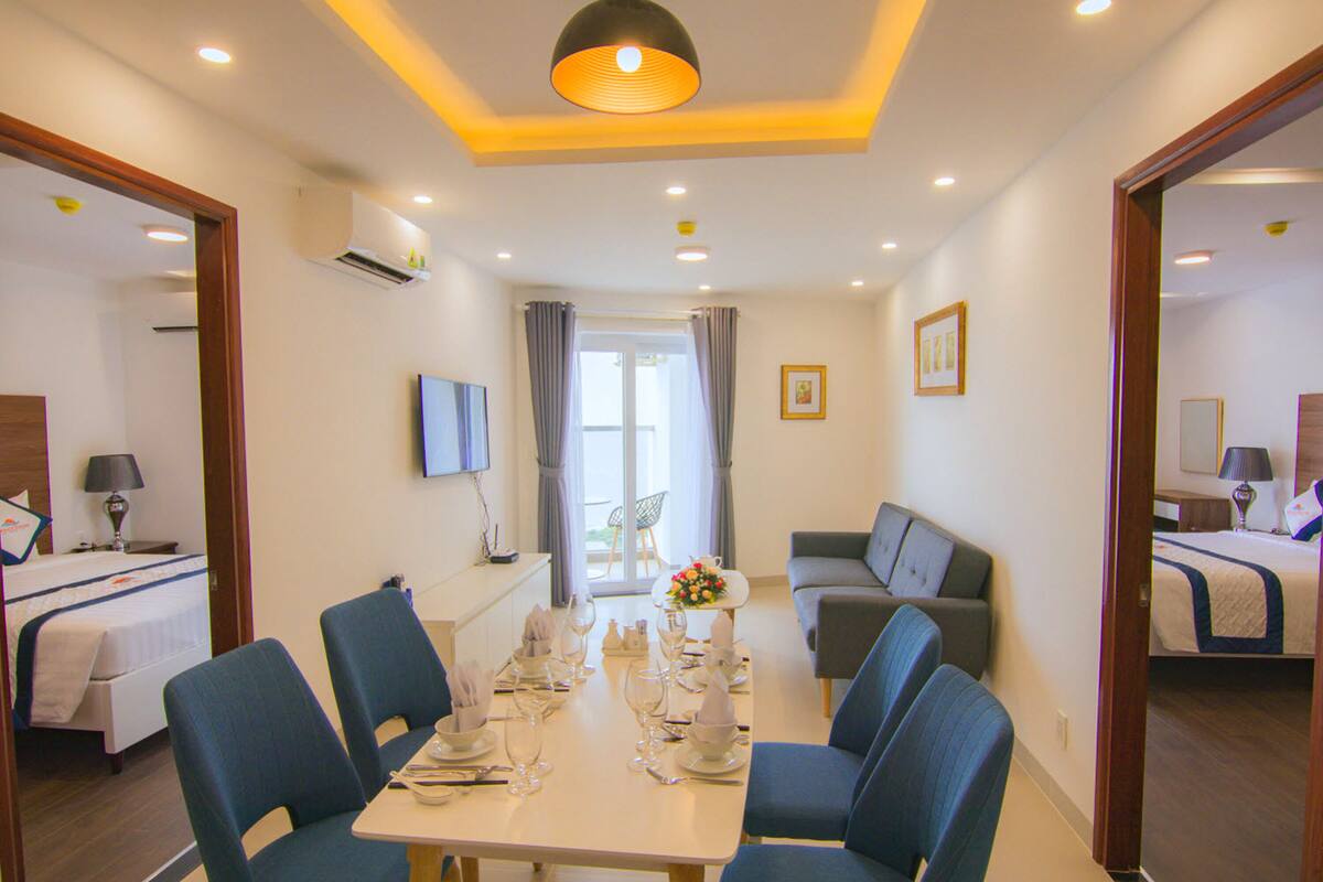 A hotel room with a dining area, a sofa, a TV, and a bed.