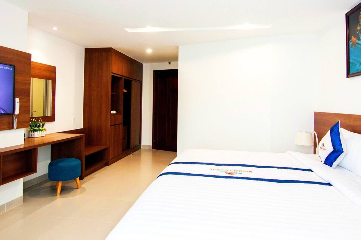 A hotel room with a bed, a TV, a desk, and a wardrobe.