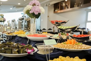 A buffet with various dishes, including a plate labeled "CHÁ LÜA" and a bowl of salad.