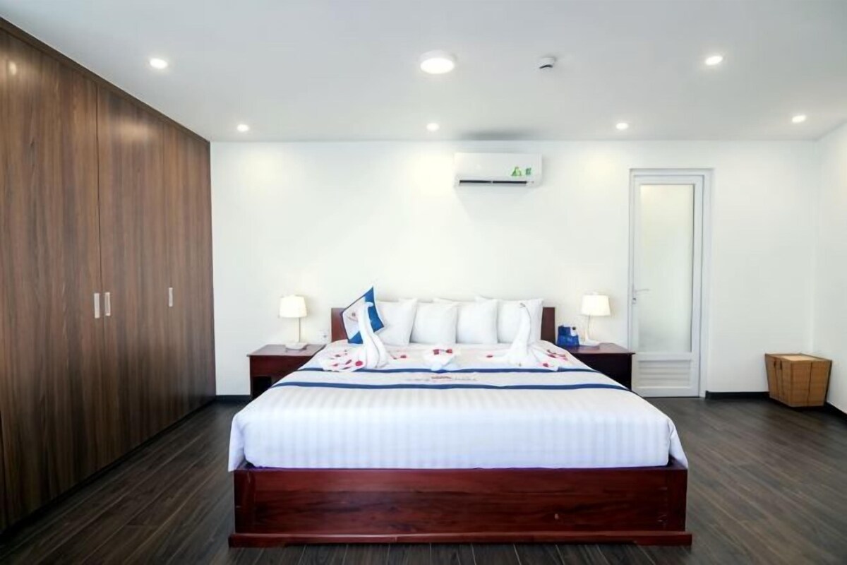 Una habitación de hotel con una cama grande, un armario, una mesita de noche y aire acondicionado instalado en la pared.