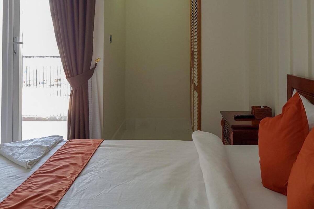 A hotel room with a bed, a nightstand, and a view of the outside balcony.