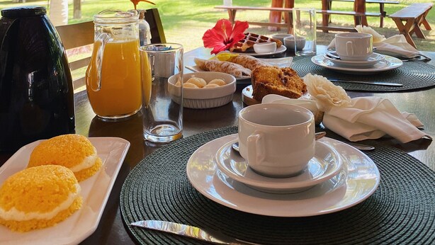 Une table dressée pour le petit-déjeuner, avec une vue tropicale comprenant des palmiers et une piscine.