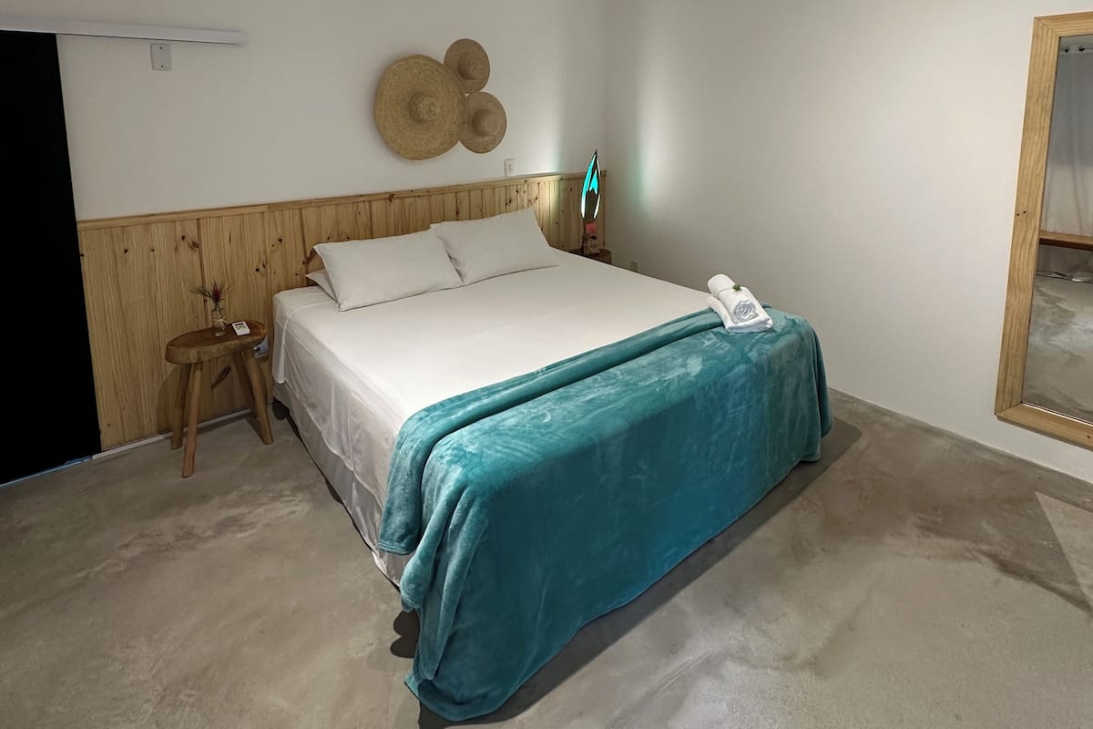 Ein Schlafzimmer mit einem Bett, einem Nachttisch, einer Wandlampe und einem hölzernen Kopfteil.