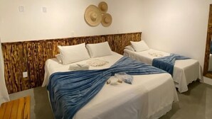 Une chambre d’hôtel avec deux lits, une tête de lit en bois, un décor mural en forme de chapeau et une petite table en bois.