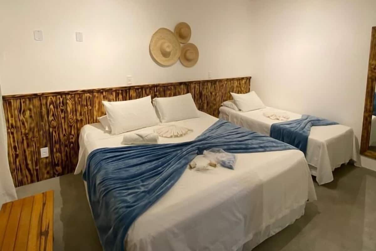 Ein Hotelzimmer mit zwei Betten, einem Holz-Kopfteil, einer Wanddekoration mit Hut und einem kleinen Holztisch.