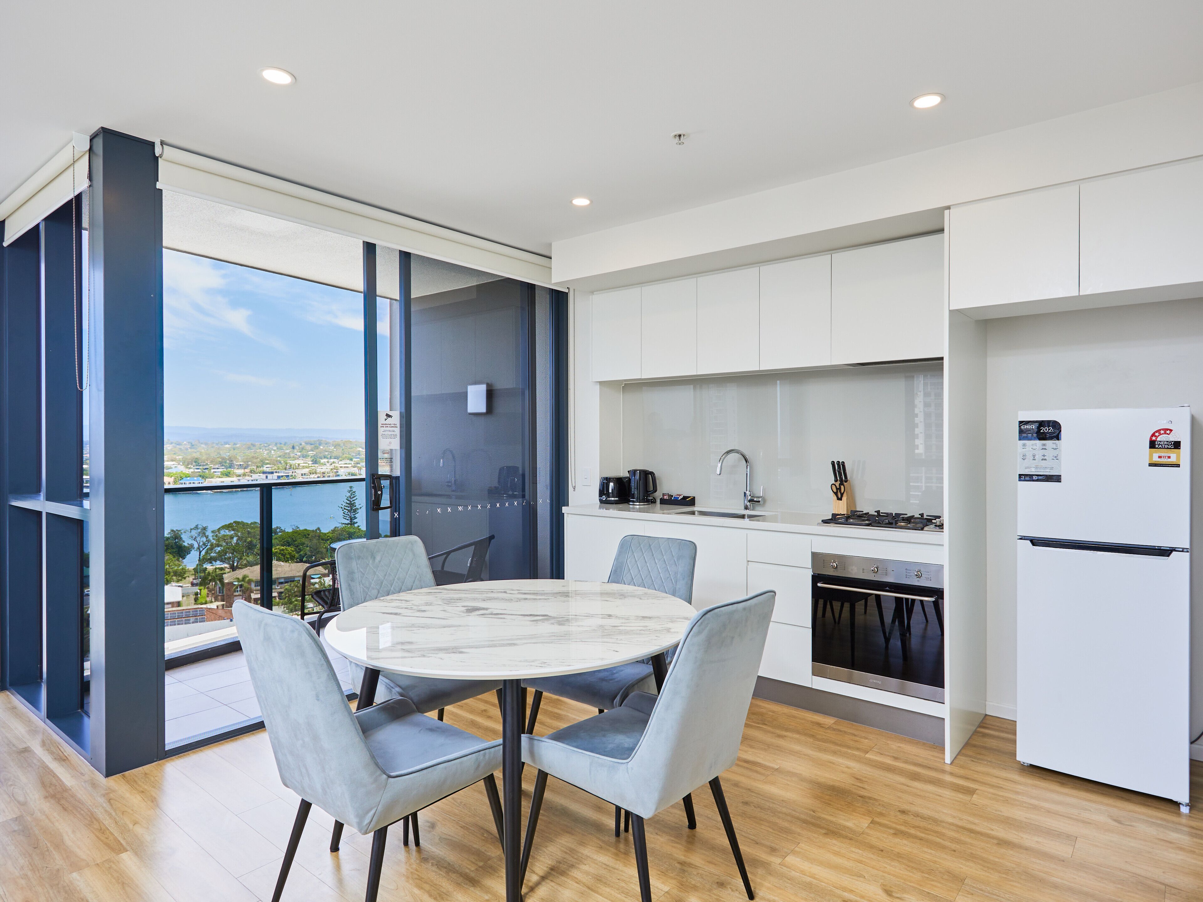 A modern kitchen with white cabinets, a built-in oven, and a refrigerator.