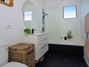 Bathroom features a white vanity, black bathtub, and glass-enclosed shower area.
