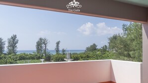Un balcone con vista sul mare e sugli alberi.