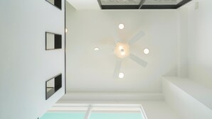 Un interno moderno con una ventola a soffitto, illuminazione a incasso e un lucernario.