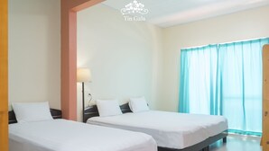 Una camera d'albergo con due letti singoli, un comodino, una lampada e una finestra con tende.