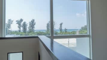 A large window with a view of the ocean and trees.