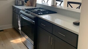 Una cucina moderna con mobili scuri, elettrodomestici in acciaio inossidabile e un'ampia finestra che permette l'ingresso di luce naturale.