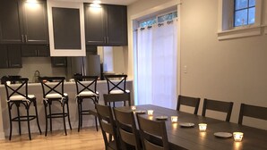 Una cucina moderna con mobili scuri, un tavolo da pranzo in legno con sei sedie e luci a incasso.