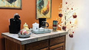 Un comptoir de cuisine avec une machine à café, une bouilloire et un vase décoratif rempli de fleurs.