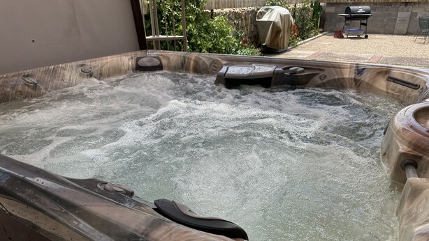 Un bain à remous doté d’une structure extérieure en bois, d’un panneau de commande et d’une pompe.