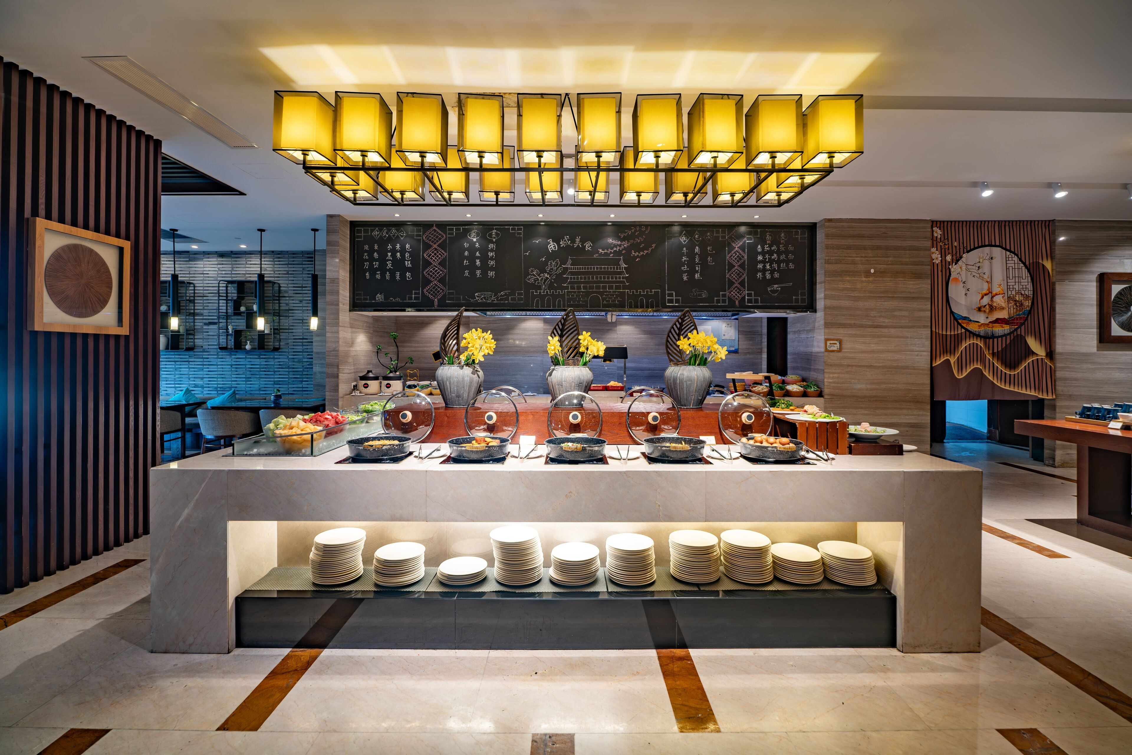 Zona de buffet con varias estaciones de comida, una barra de servicio central y un área de asientos al fondo.