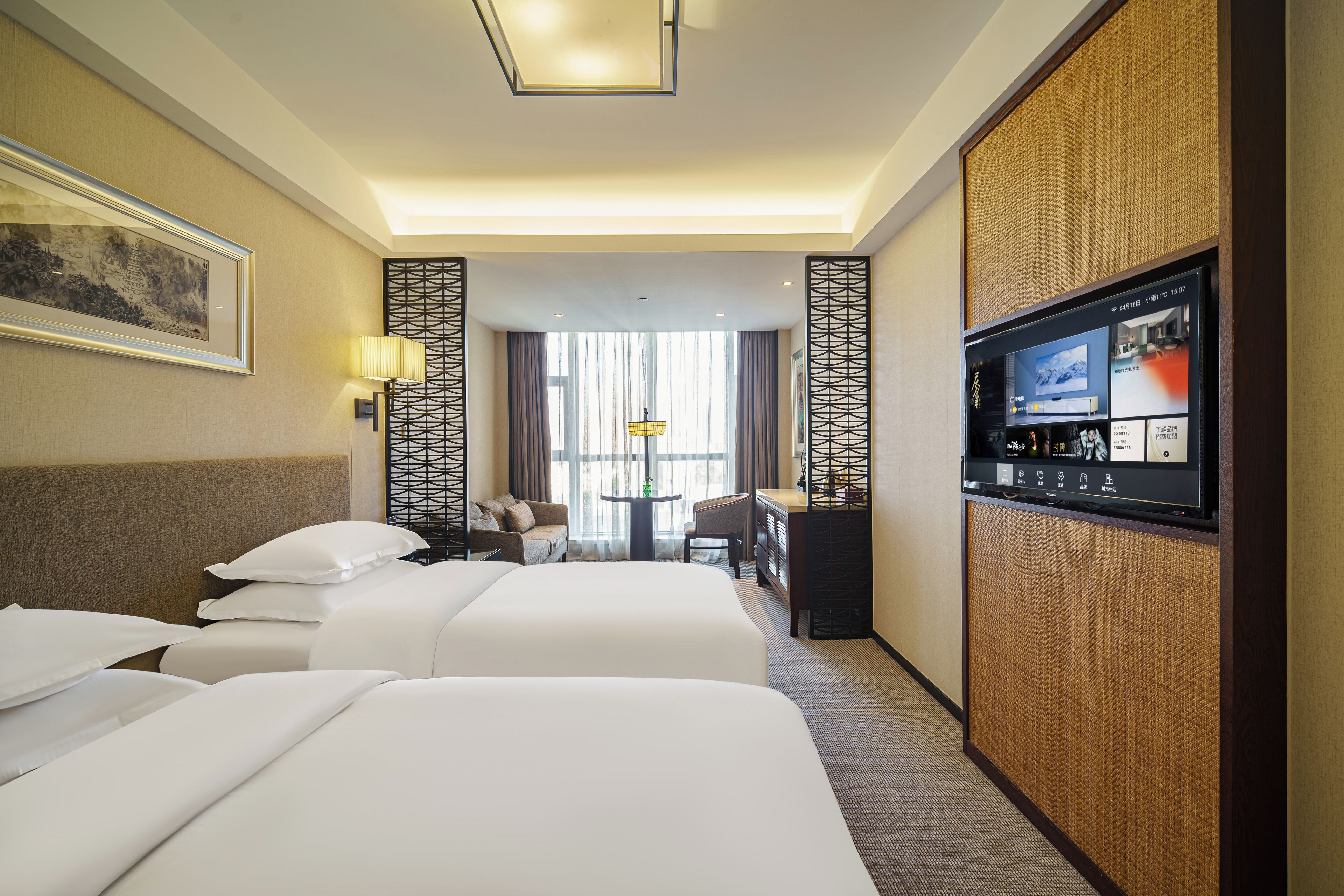 Une chambre d’hôtel avec deux lits, un bureau, une télévision et une grande fenêtre.