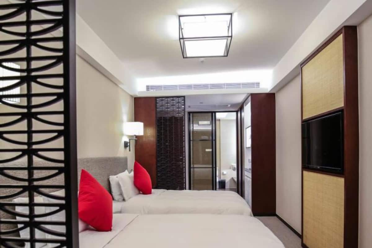 A hotel room with a bed, a TV, and a decorative screen.